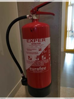Extincteur à poudre sur support au sol dans un local